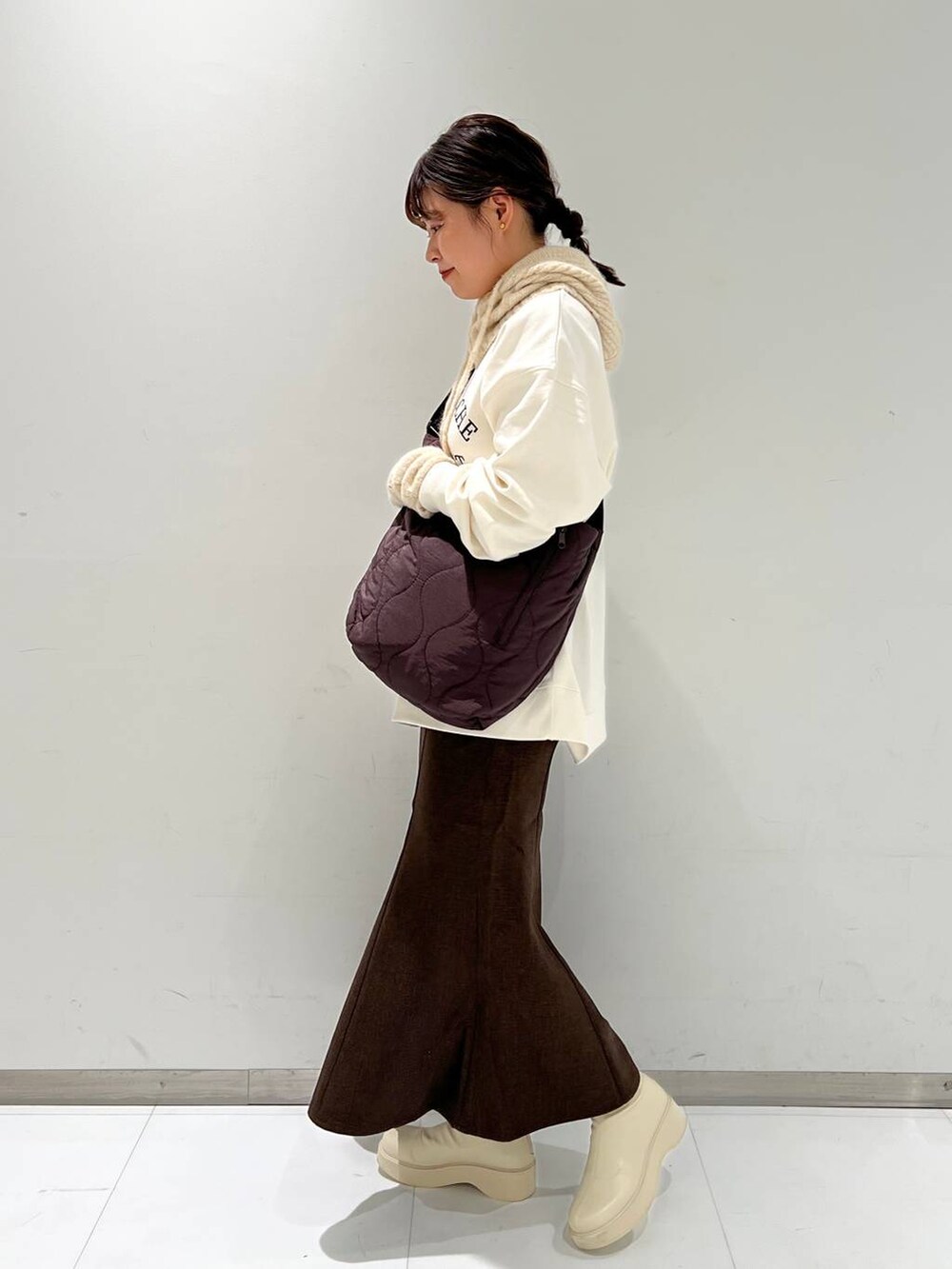 ホワイト系のスウェット、ホワイト系のブーツ、ブラウン系のスカートを着用したレディースの秋コーディネートの3枚目の写真