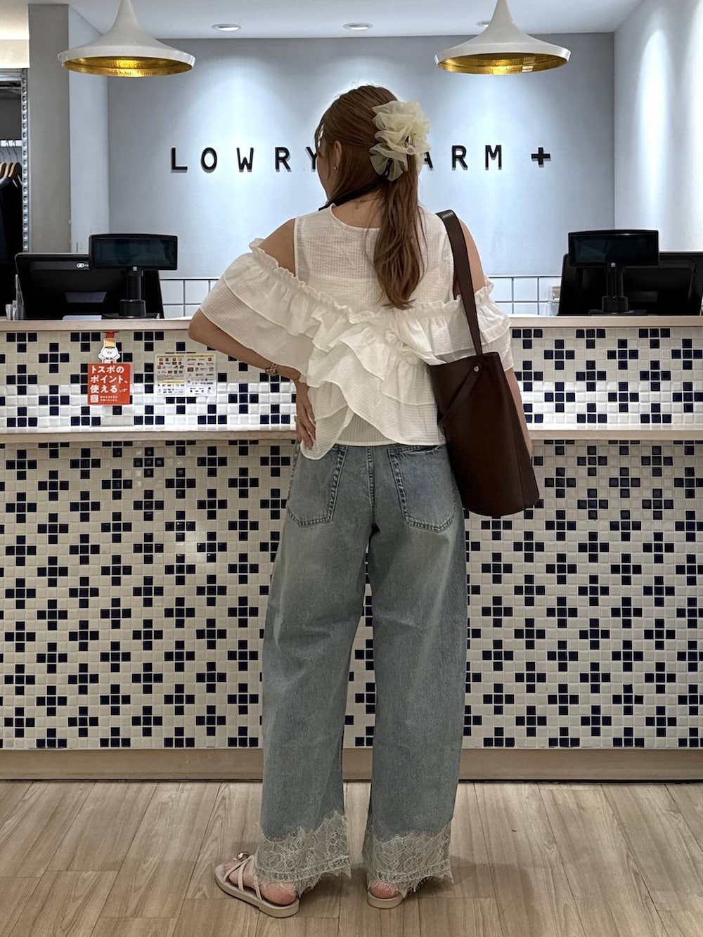 ブルー系のデニムパンツ、ホワイト系のサンダル、ブラウン系のトートバッグを着用したレディースの夏コーディネートの7枚目の写真