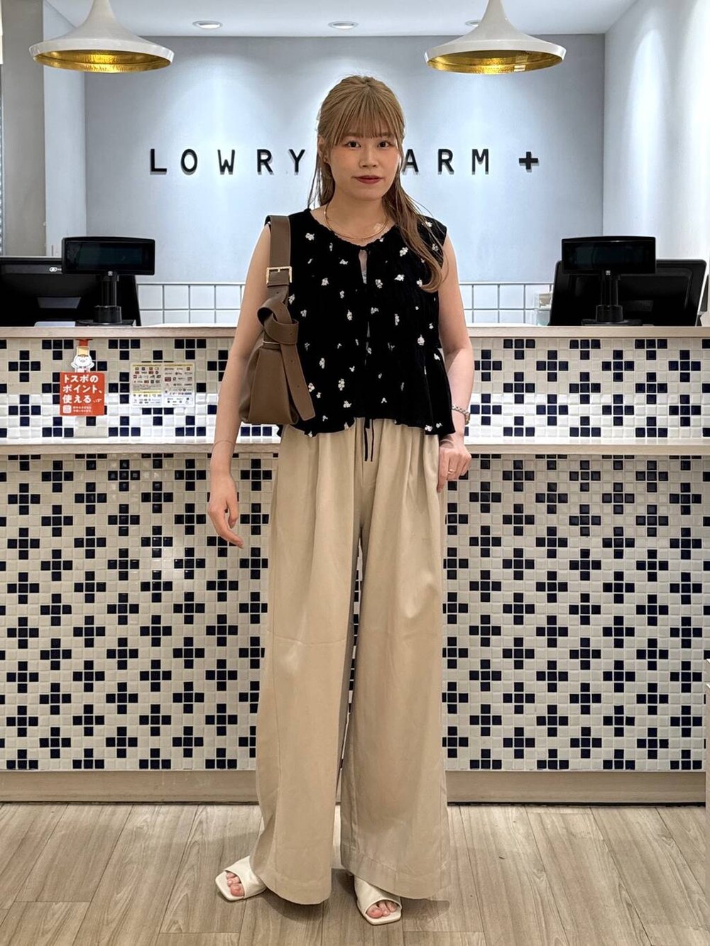ベージュ系のデニムパンツ、ブラウン系のショルダーバッグ、ホワイト系のサンダルを着用したレディースの夏コーディネートの2枚目の写真