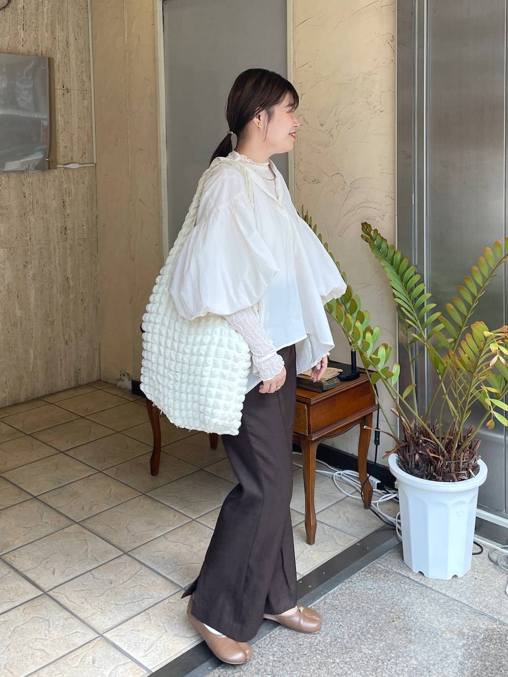 ホワイト系のショルダーバッグ、ホワイト系のTシャツ/カットソー、ブラウン系のスラックスを着用したレディースの秋コーディネートの3枚目の写真