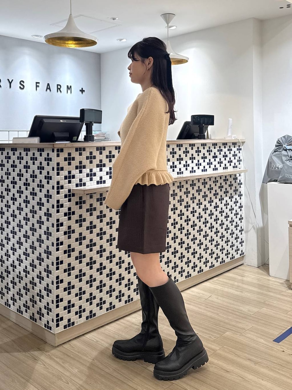 ブラウン系のステンカラーコート、ブラウン系のその他パンツ、ブラック系のブーツを着用したレディースの秋コーディネートの7枚目の写真