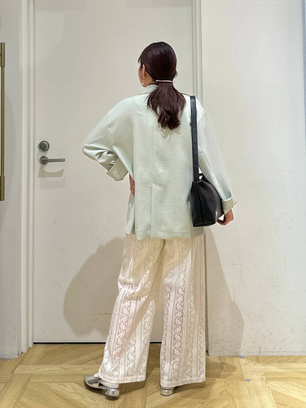 グリーン系のテーラードジャケット、ゴールド系のタンクトップ、シルバー系のパンプスを着用したレディースの春コーディネートの4枚目の写真