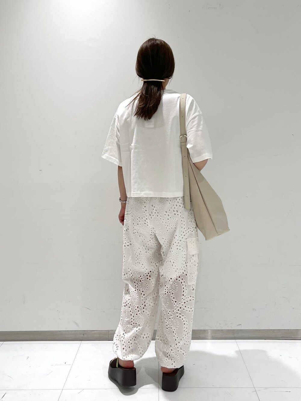 ブラウン系のサンダル、ホワイト系のカーゴパンツ、シルバー系のショルダーバッグを着用したレディースの夏コーディネートの3枚目の写真