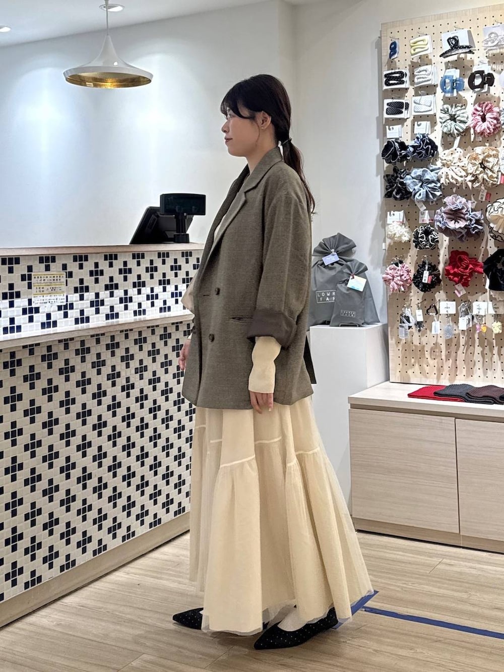 ブラック系のパンプス、ブラウン系のテーラードジャケット、ベージュ系のショルダーバッグを着用したレディースの春コーディネートの4枚目の写真