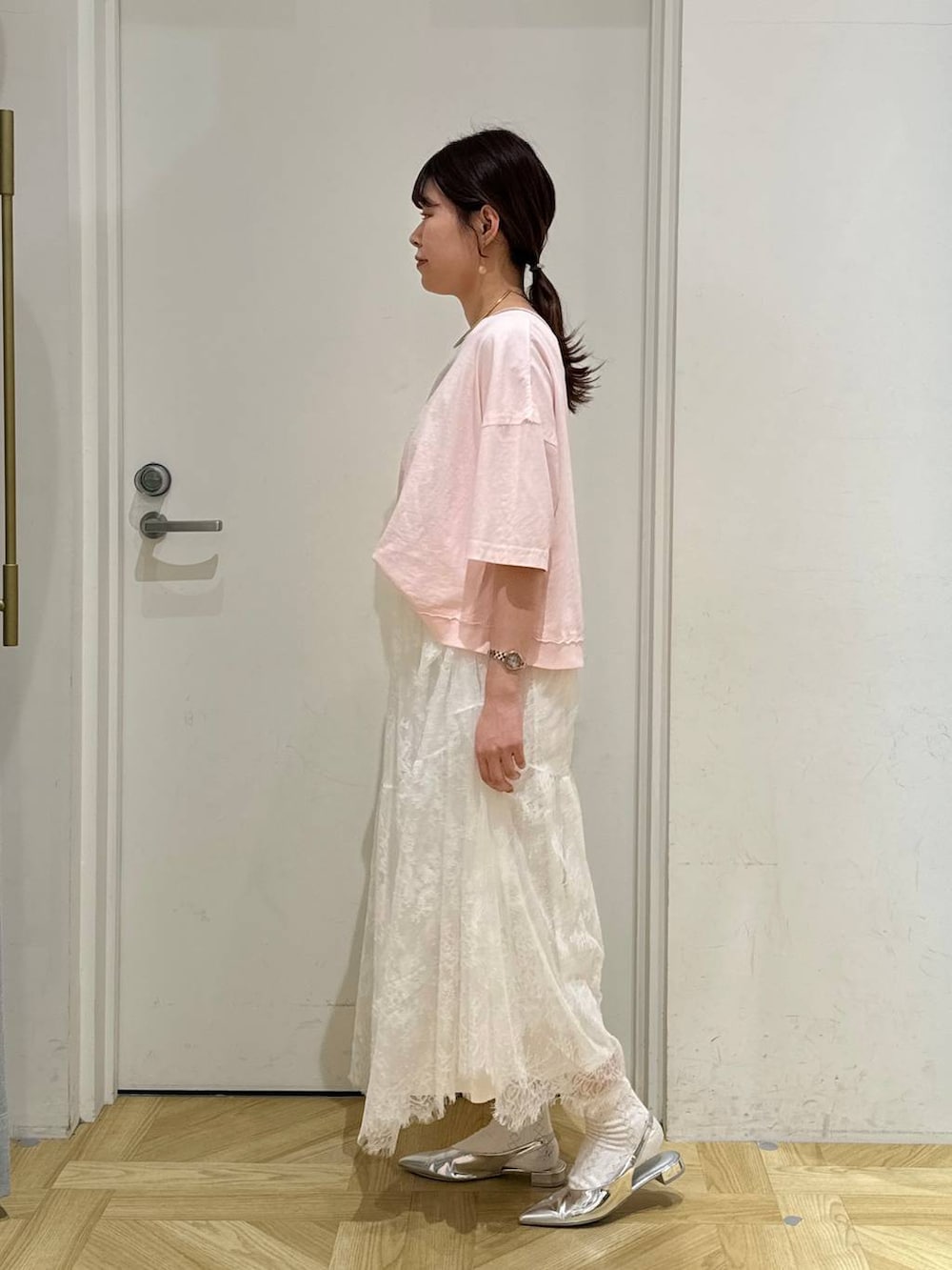 シルバー系のトートバッグ、シルバー系のパンプス、ホワイト系のスカートを着用したレディースの春コーディネートの4枚目の写真