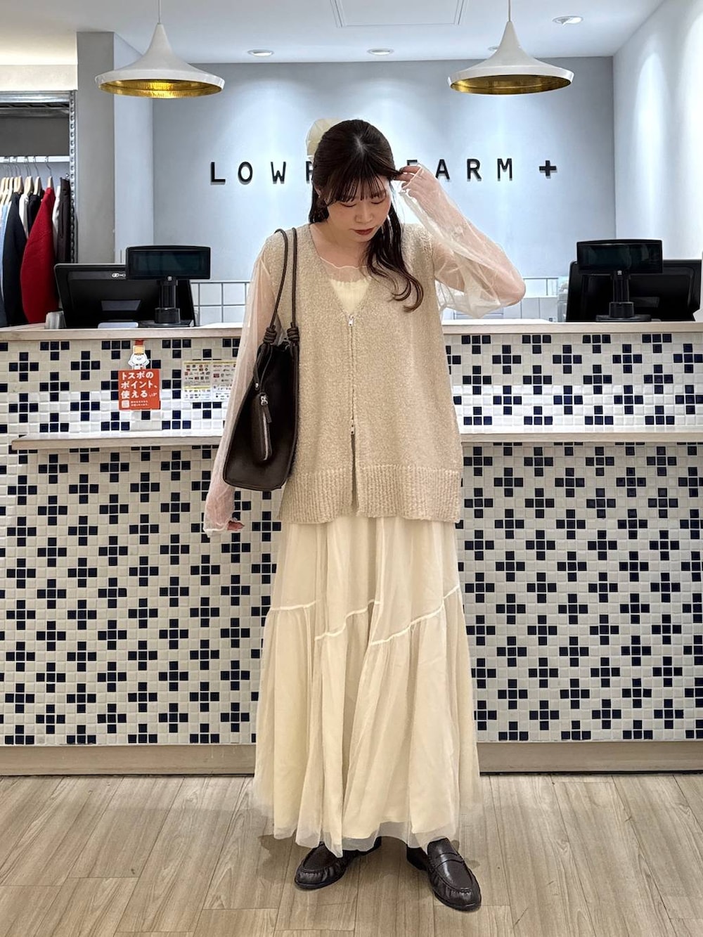 ブラウン系のローファー、ブラウン系のトートバッグ、ホワイト系のスカートを着用したレディースの春コーディネートの4枚目の写真