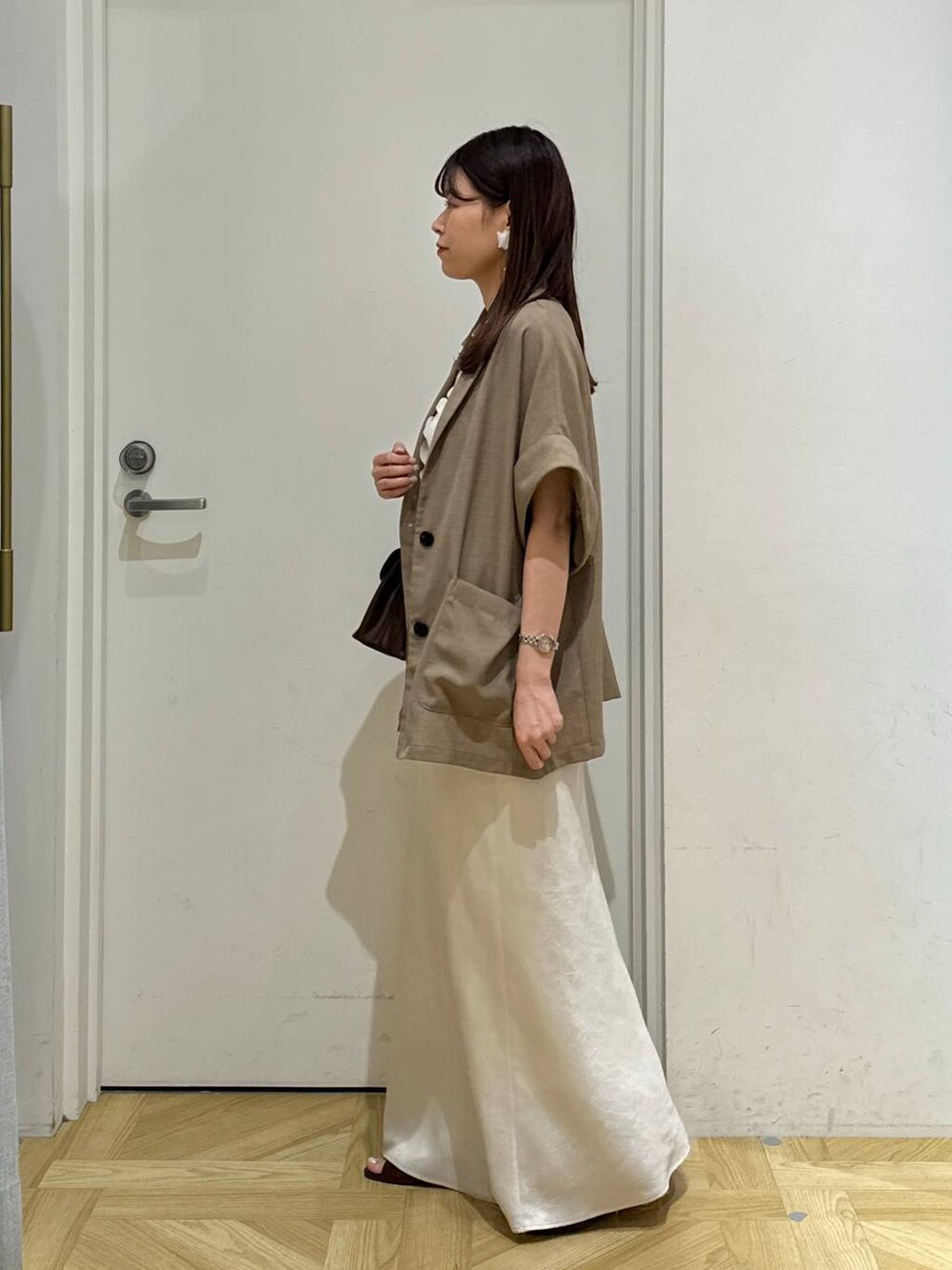 ブラウン系のスカート、ベージュ系のテーラードジャケット、ブラウン系のサンダルを着用したレディースの夏コーディネートの3枚目の写真