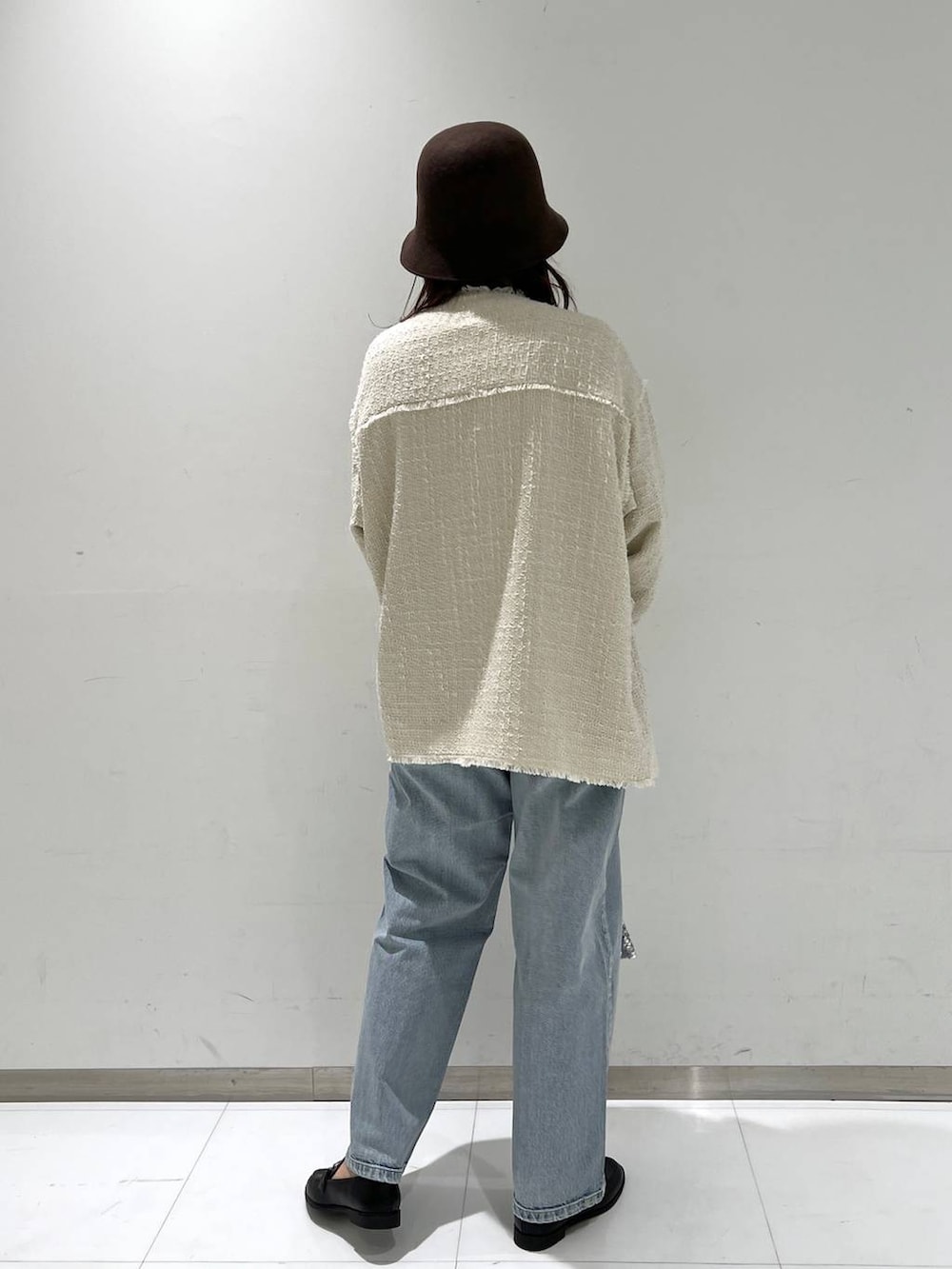 ブルー系のデニムパンツ、ブラック系のローファー、ホワイト系のノーカラージャケットを着用したレディースの秋コーディネートの5枚目の写真