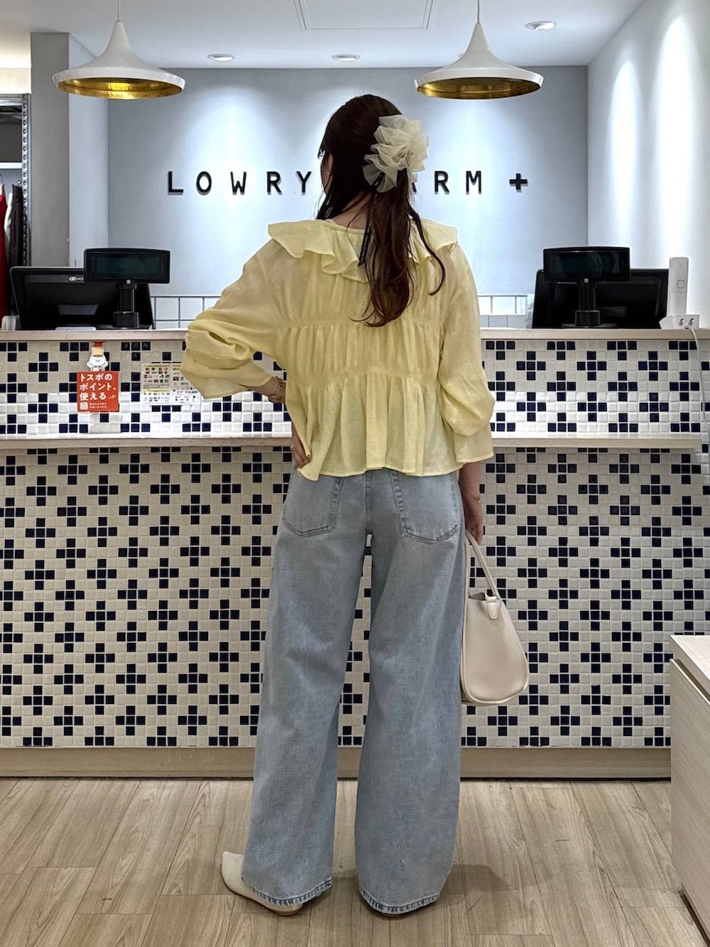 ホワイト系のショルダーバッグ、ブルー系のデニムパンツ、ホワイト系のパンプスを着用したレディースの春コーディネートの3枚目の写真