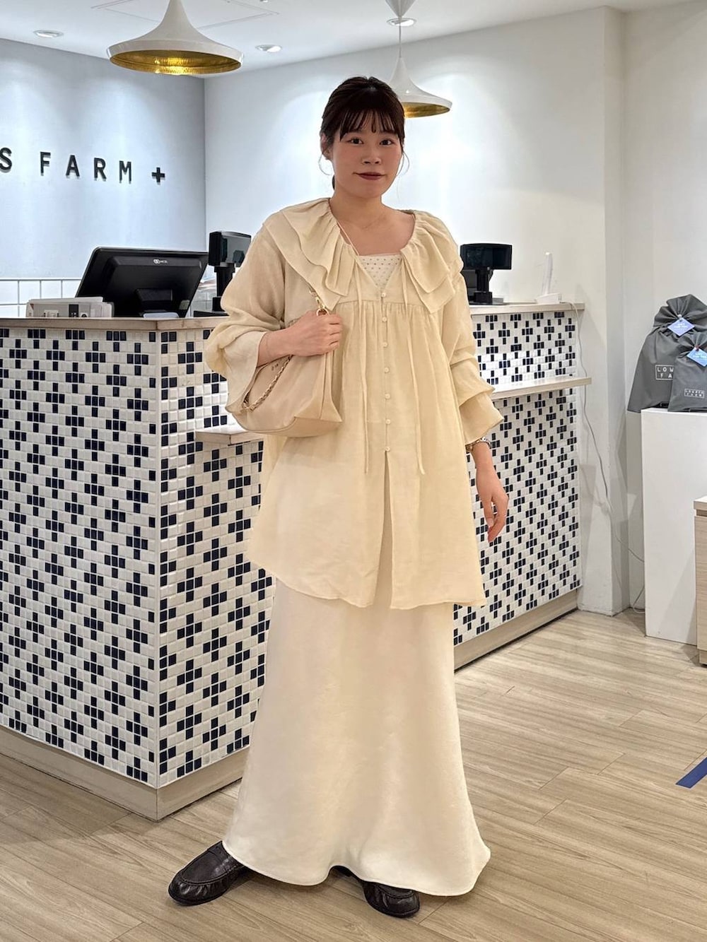 ホワイト系のスカート、ベージュ系のショルダーバッグ、ブラウン系のローファーを着用したレディースの春コーディネートの2枚目の写真