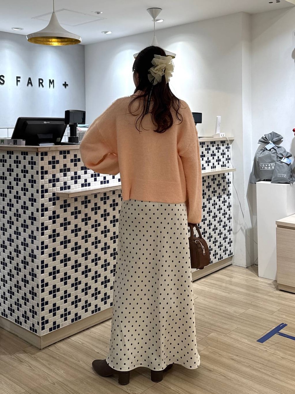 ホワイト系のスカート、ブラウン系のボストンバッグ、ブラウン系のブーツを着用したレディースの冬コーディネートの5枚目の写真