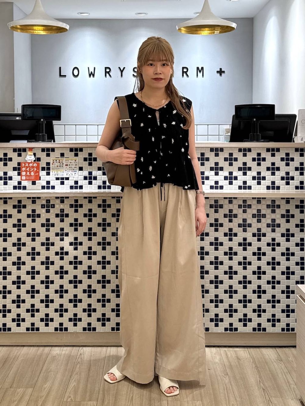 ベージュ系のデニムパンツ、ブラウン系のショルダーバッグ、ホワイト系のサンダルを着用したレディースの夏コーディネートの3枚目の写真