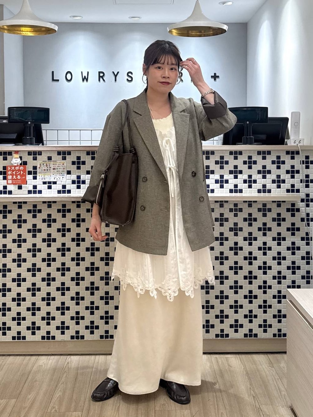 ホワイト系のスカート、ブラウン系のテーラードジャケット、ブラウン系のローファーを着用したレディースの春コーディネートの3枚目の写真