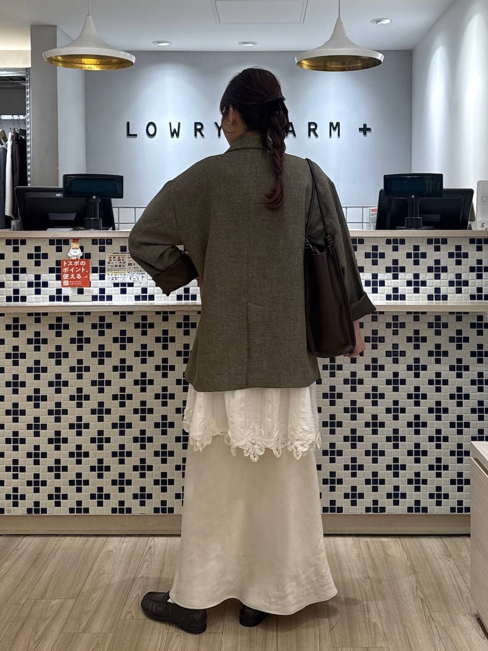 ホワイト系のスカート、ブラウン系のテーラードジャケット、ブラウン系のローファーを着用したレディースの春コーディネートの6枚目の写真