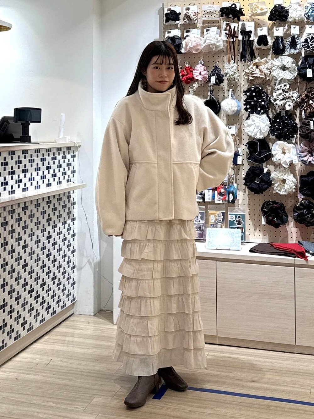 ホワイト系のブルゾン、ホワイト系のスカート、ブラウン系のポロシャツを着用したレディースの秋コーディネートの3枚目の写真