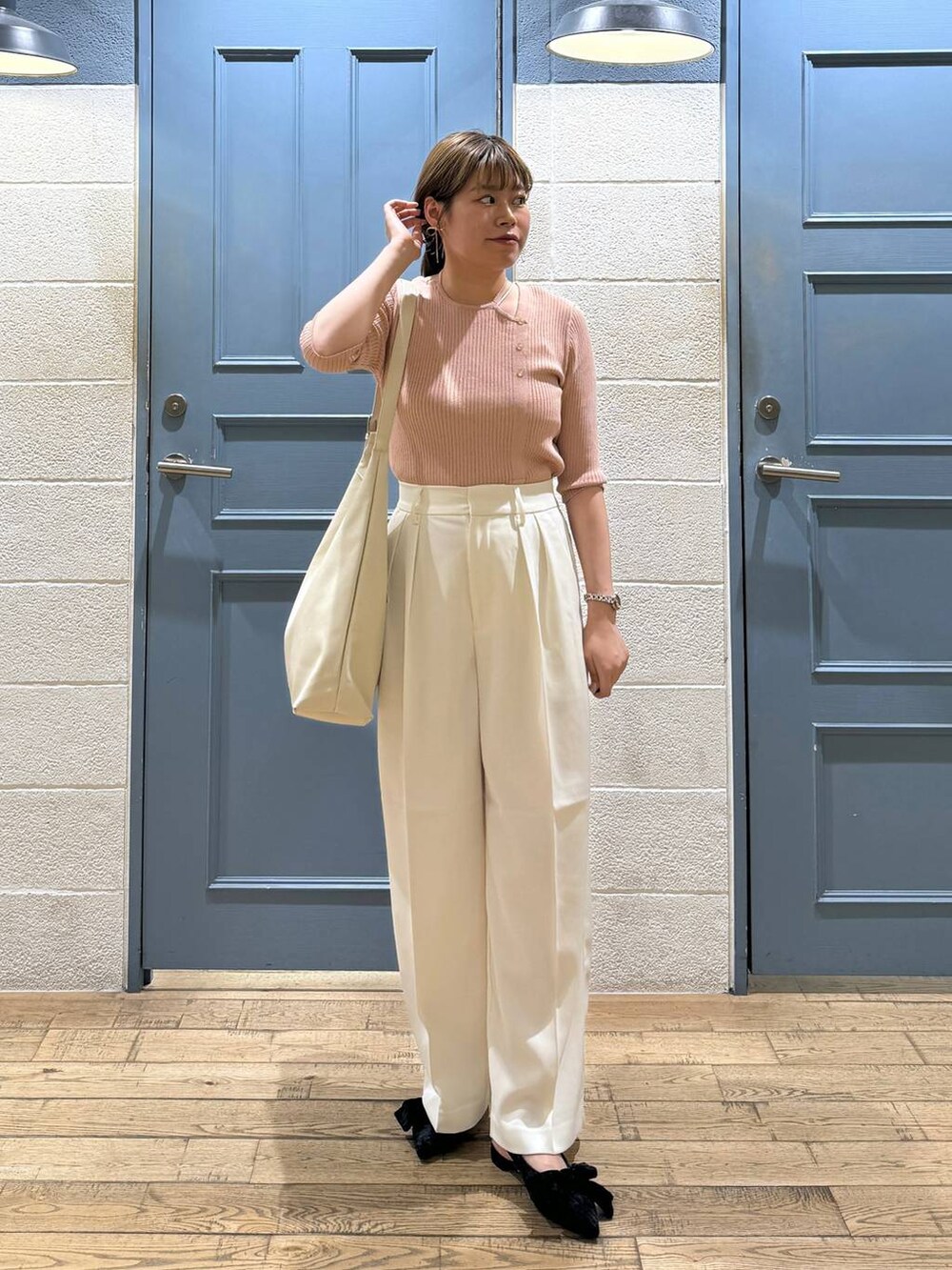 ブラック系のパンプス、ホワイト系のショルダーバッグ、ホワイト系のスラックスを着用したレディースの夏コーディネートの2枚目の写真