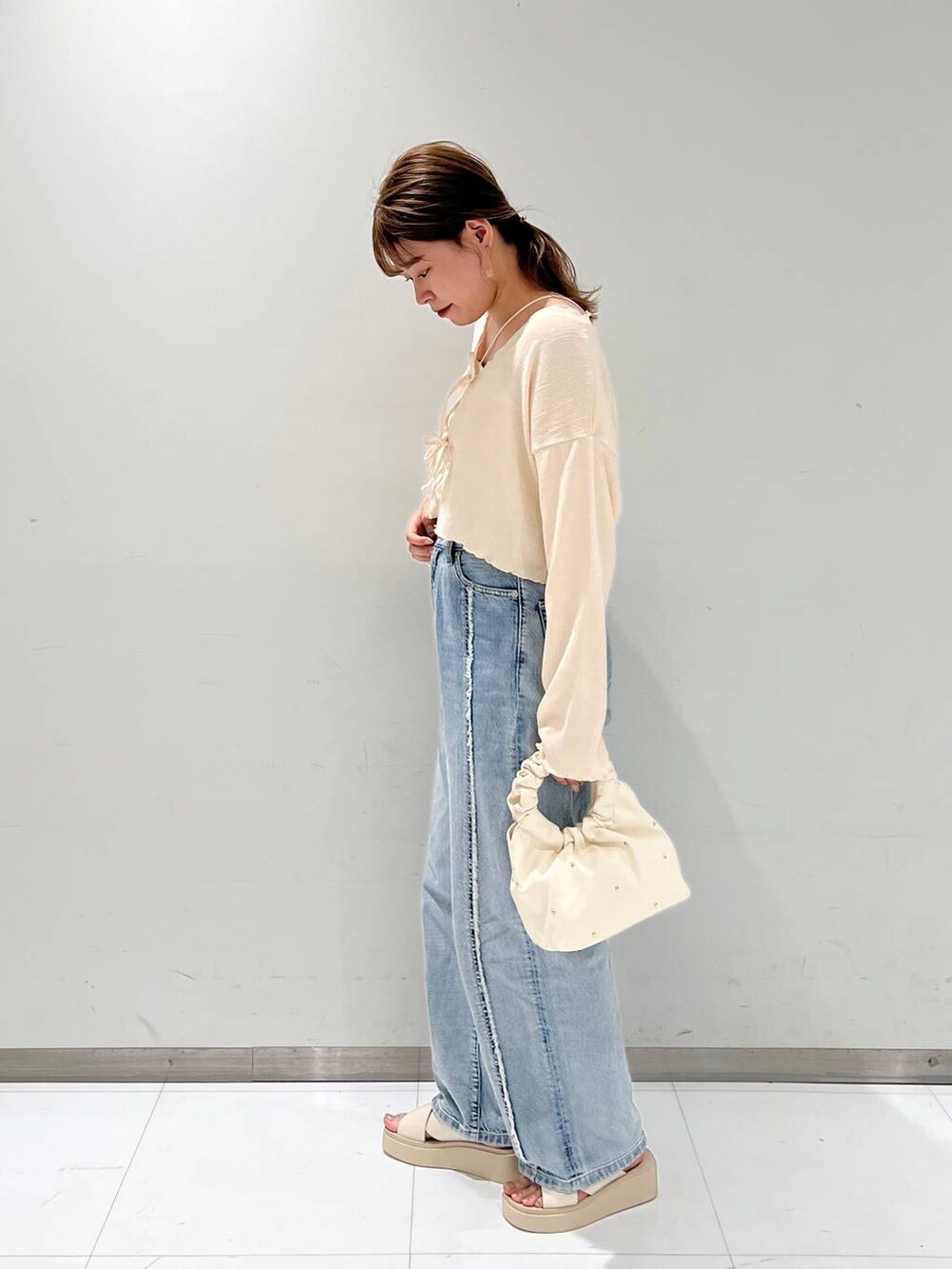 ベージュ系のハンドバッグ、ホワイト系のサンダル、ホワイト系のタンクトップを着用したレディースの夏コーディネートの2枚目の写真