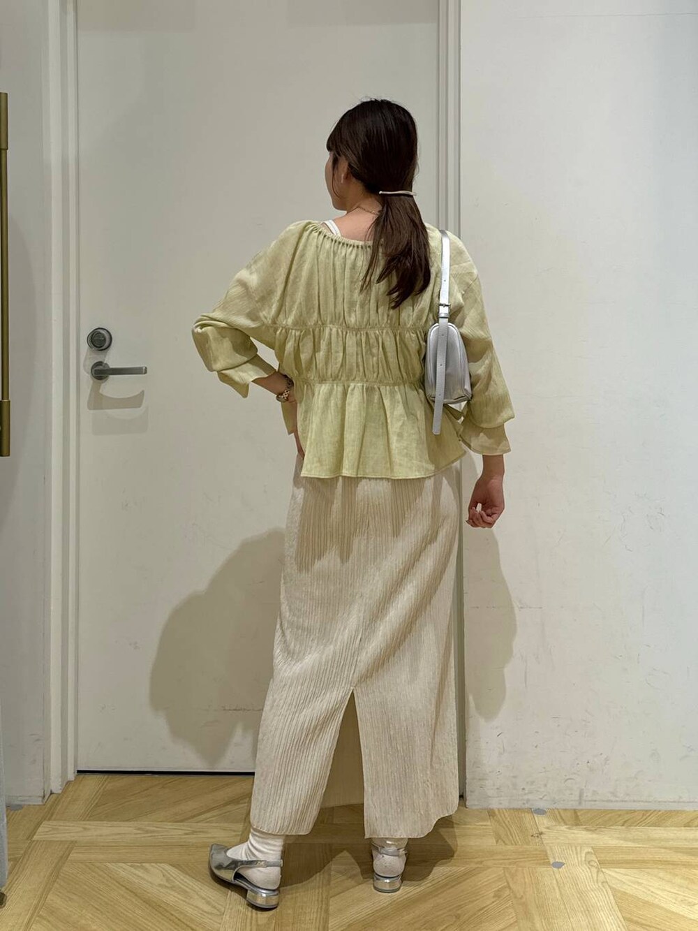 シルバー系のトートバッグ、シルバー系のパンプス、ホワイト系のスカートを着用したレディースの春コーディネートの5枚目の写真