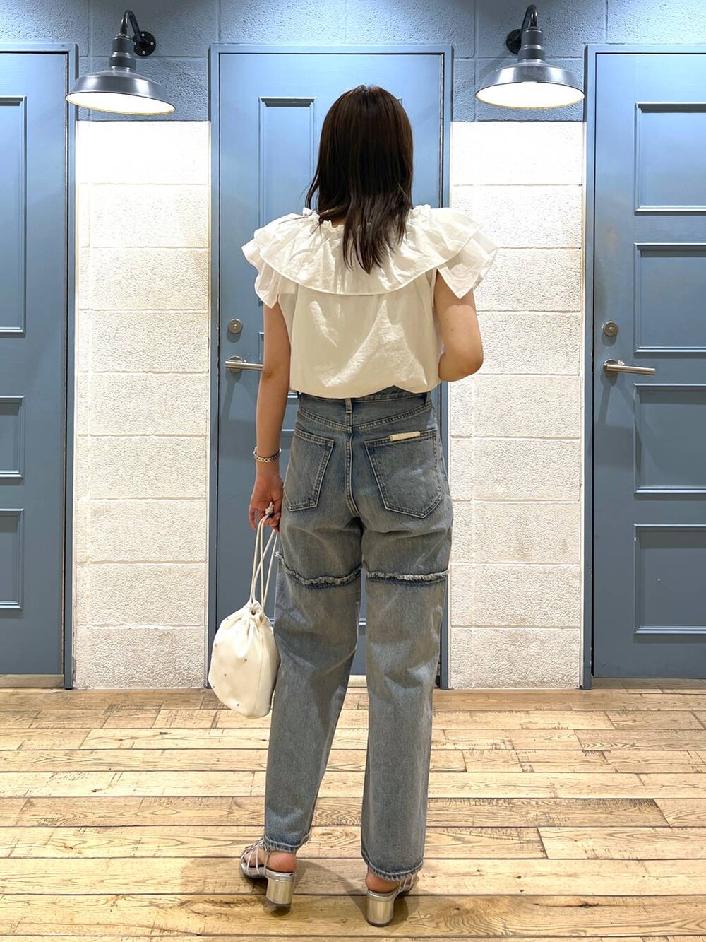 ホワイト系のショルダーバッグ、シルバー系のサンダル、ブルー系のデニムパンツを着用したレディースの夏コーディネートの3枚目の写真