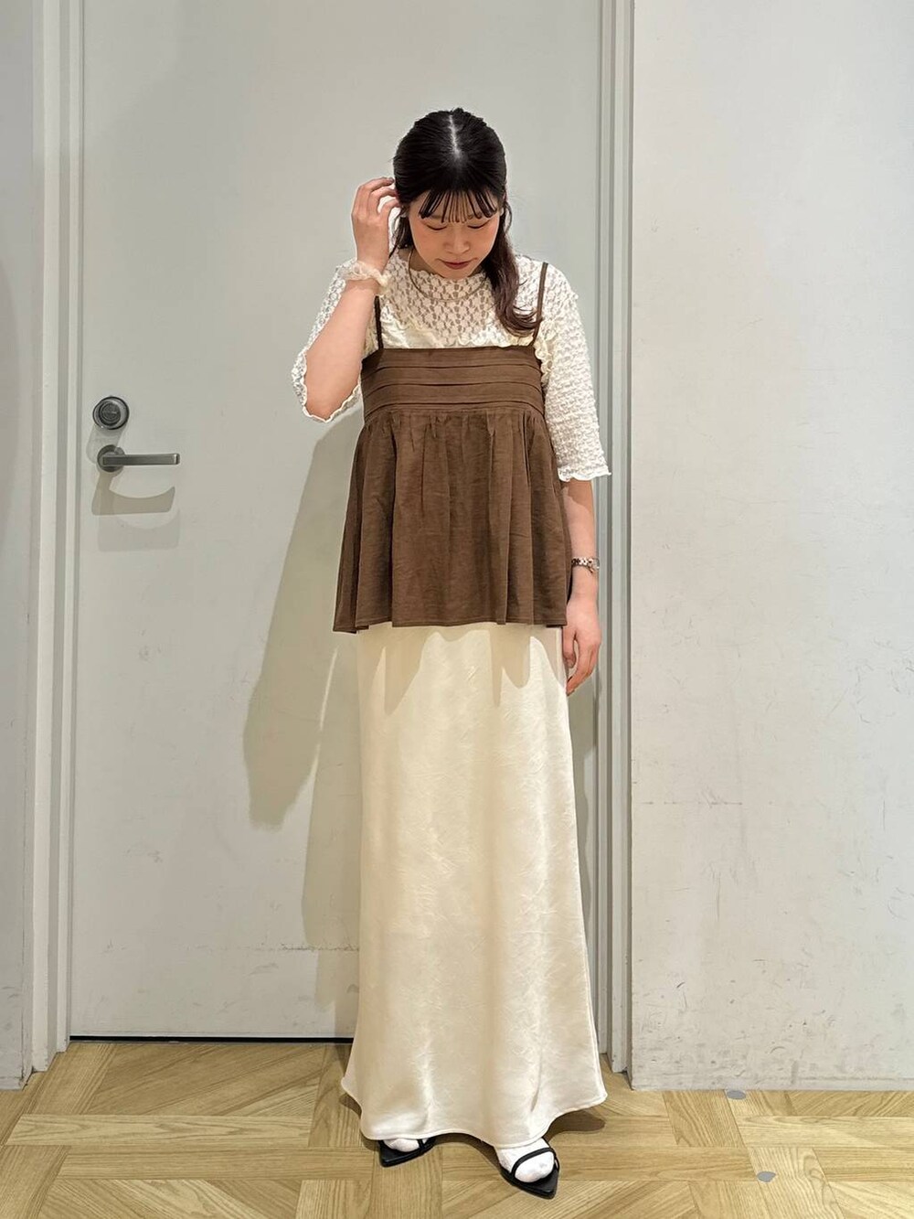ブラウン系のキャミソール、ブラック系のサンダル、ホワイト系のスカートを着用したレディースの春コーディネートの3枚目の写真