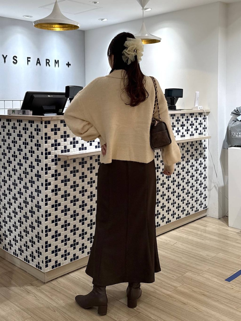 ブラウン系のスカート、ブラウン系のブーツ、ホワイト系のニット/セーターを着用したレディースの冬コーディネートの5枚目の写真