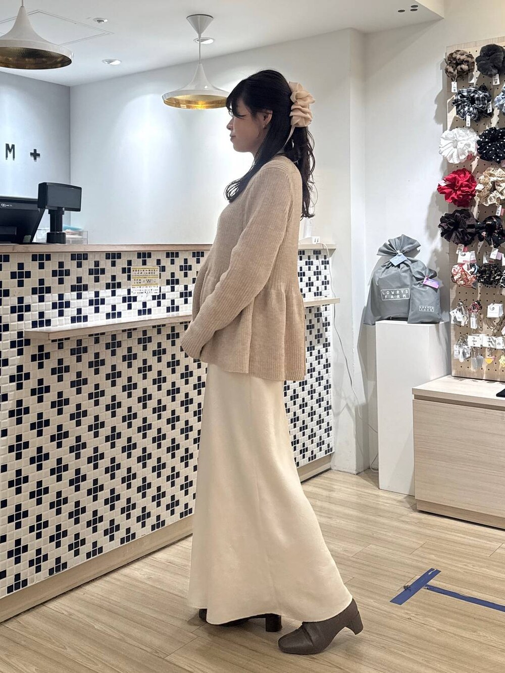 ホワイト系のスカート、ベージュ系のカーディガン/ボレロ、ブラウン系のブーツを着用したレディースの冬コーディネートの6枚目の写真