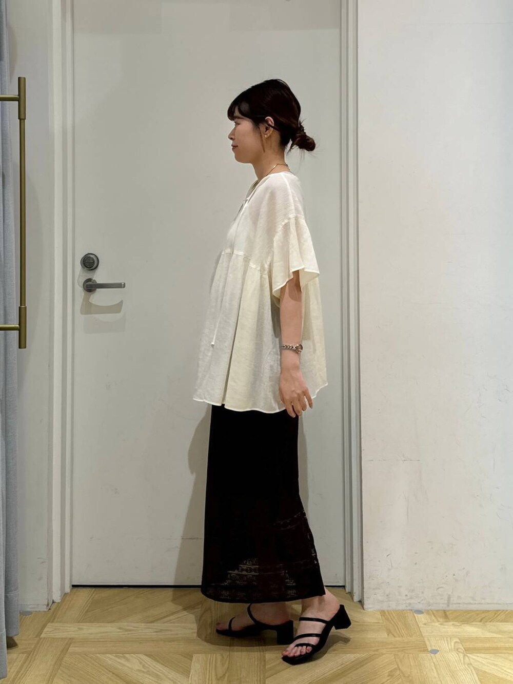 ブラック系のサンダル、ブラウン系のスカート、ホワイト系のシャツ/ブラウスを着用したレディースの夏コーディネートの3枚目の写真