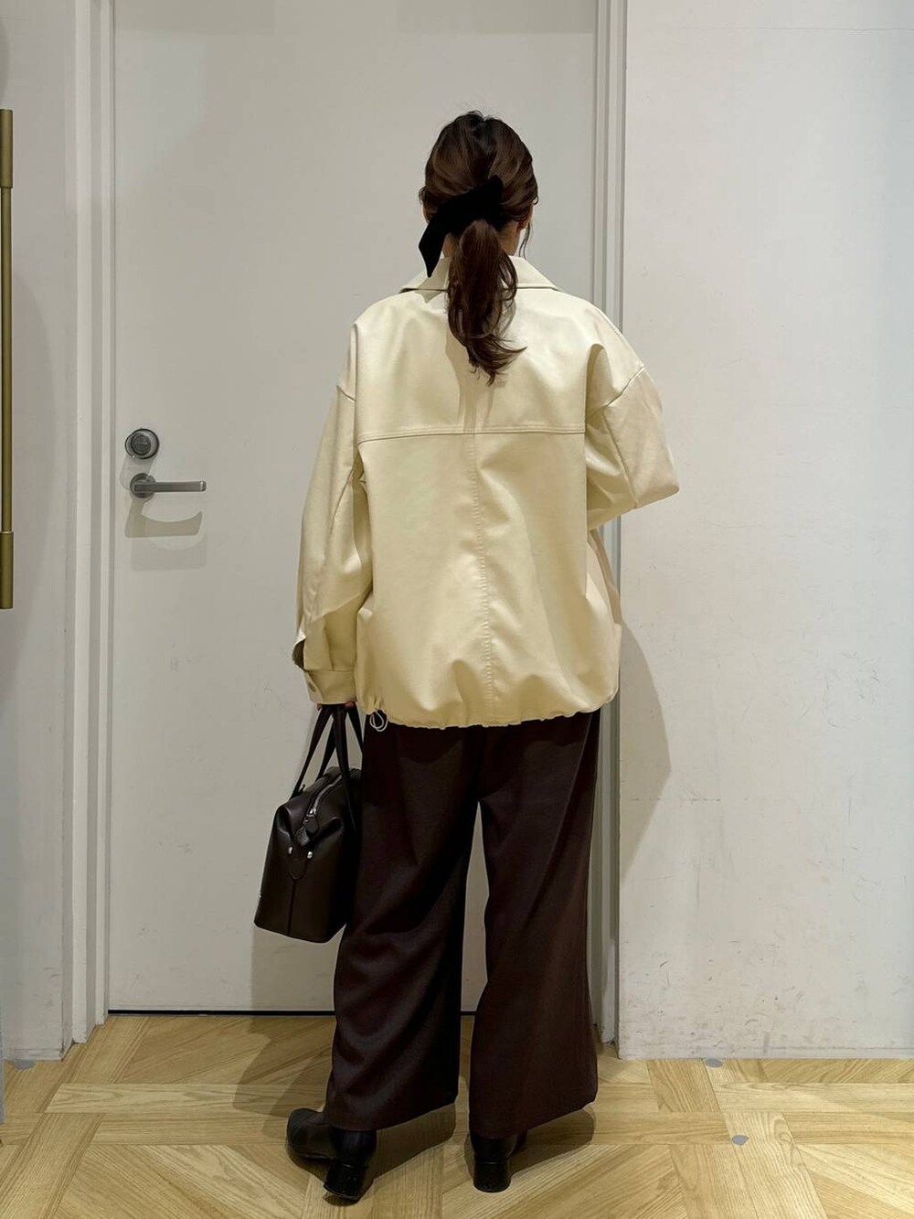 ブラック系のブーツ、ブラウン系のショルダーバッグ、ホワイト系のブルゾンを着用したレディースの冬コーディネートの4枚目の写真