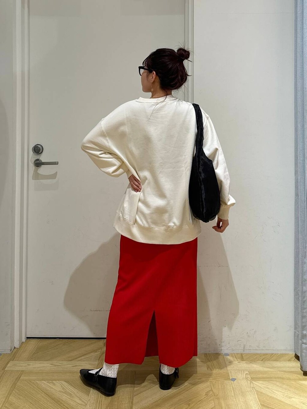 レッド系のスカート、ホワイト系のスウェット、ブラック系のバレエシューズを着用したレディースの春コーディネートの5枚目の写真
