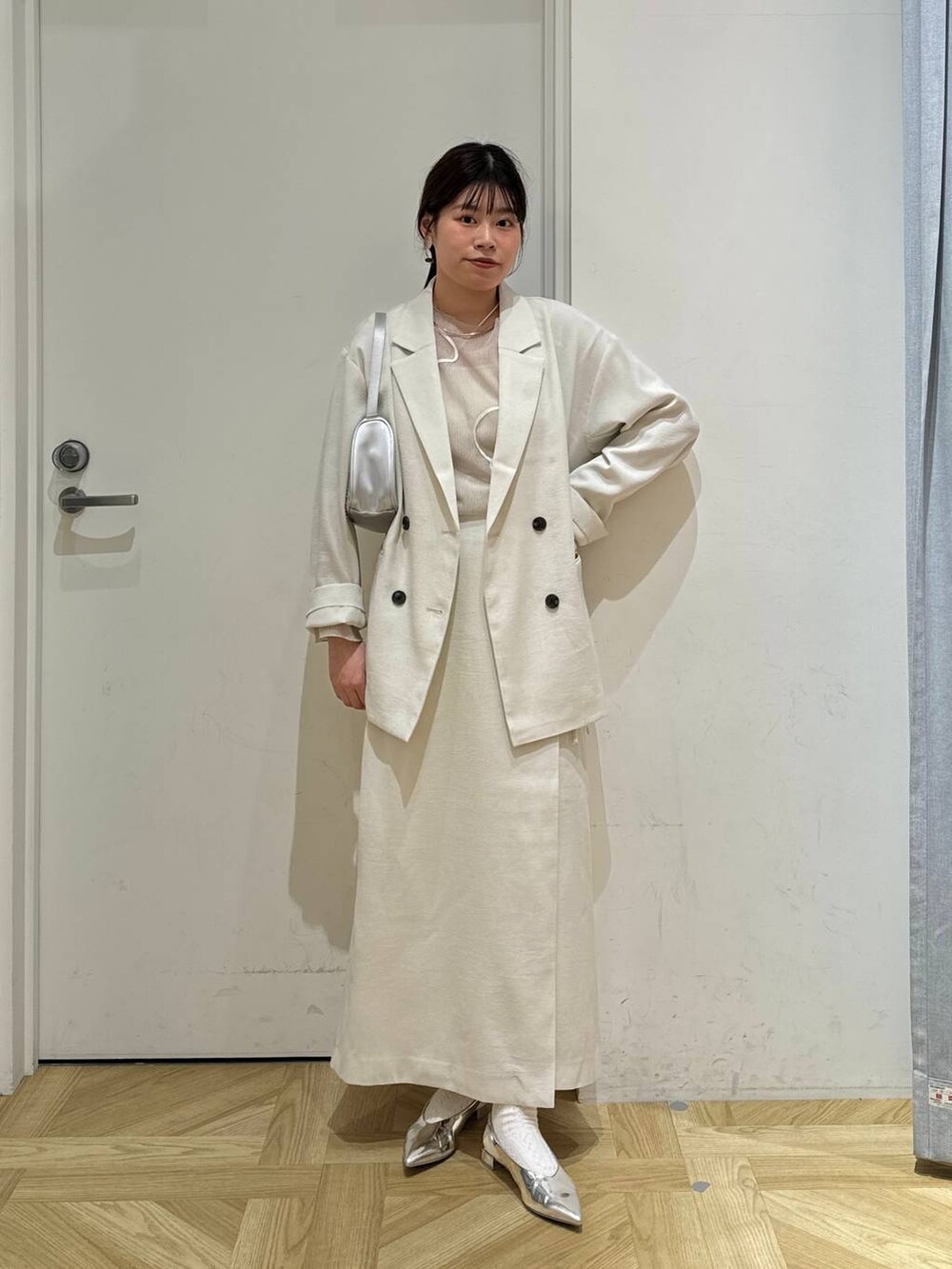 ホワイト系のスカート、ホワイト系のテーラードジャケット、シルバー系のトートバッグを着用したレディースの春コーディネートの5枚目の写真