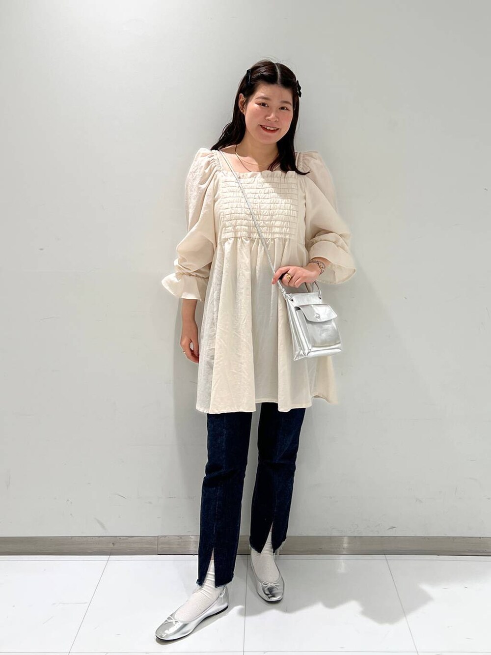 シルバー系のショルダーバッグ、グレー系のバレエシューズ、ブルー系のデニムパンツを着用したレディースの冬コーディネートの2枚目の写真