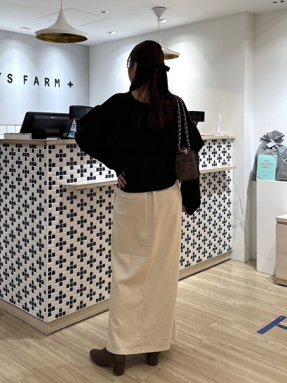 ホワイト系のスカート、ブラウン系のブーツ、ブラウン系のショルダーバッグを着用したレディースの冬コーディネートの5枚目の写真