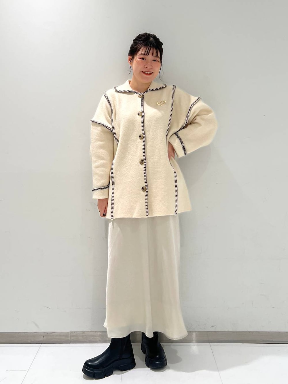 ブラック系のブーツ、ホワイト系のスカート、ホワイト系のカーディガン/ボレロを着用したレディースの秋コーディネートの2枚目の写真