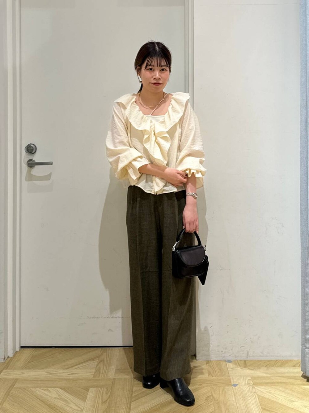 ブラック系のブーツ、ブラウン系のスラックス、ホワイト系のキャミソールを着用したレディースの春コーディネートの3枚目の写真