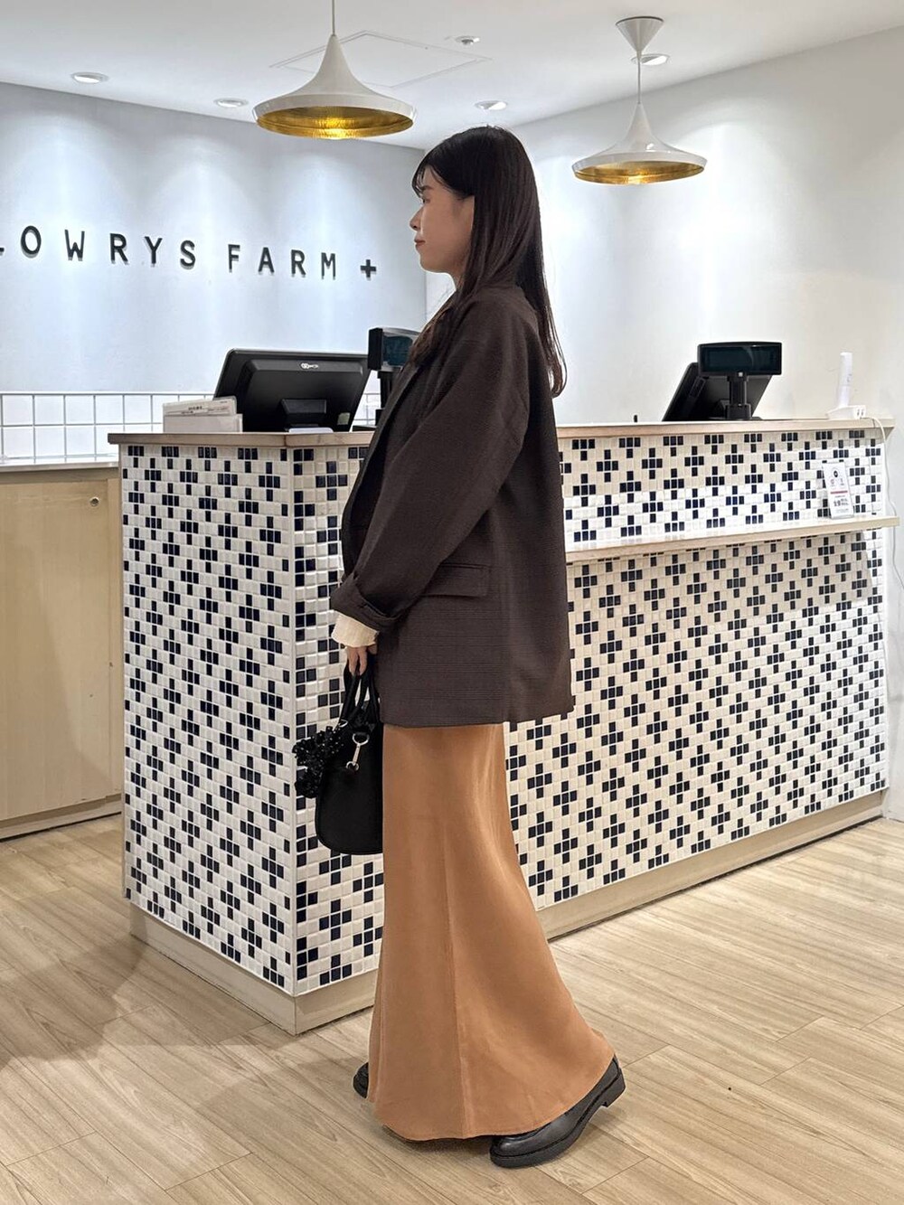 ベージュ系のTシャツ/カットソー、ブラウン系のテーラードジャケット、ブラック系のショルダーバッグを着用したレディースの秋コーディネートの3枚目の写真