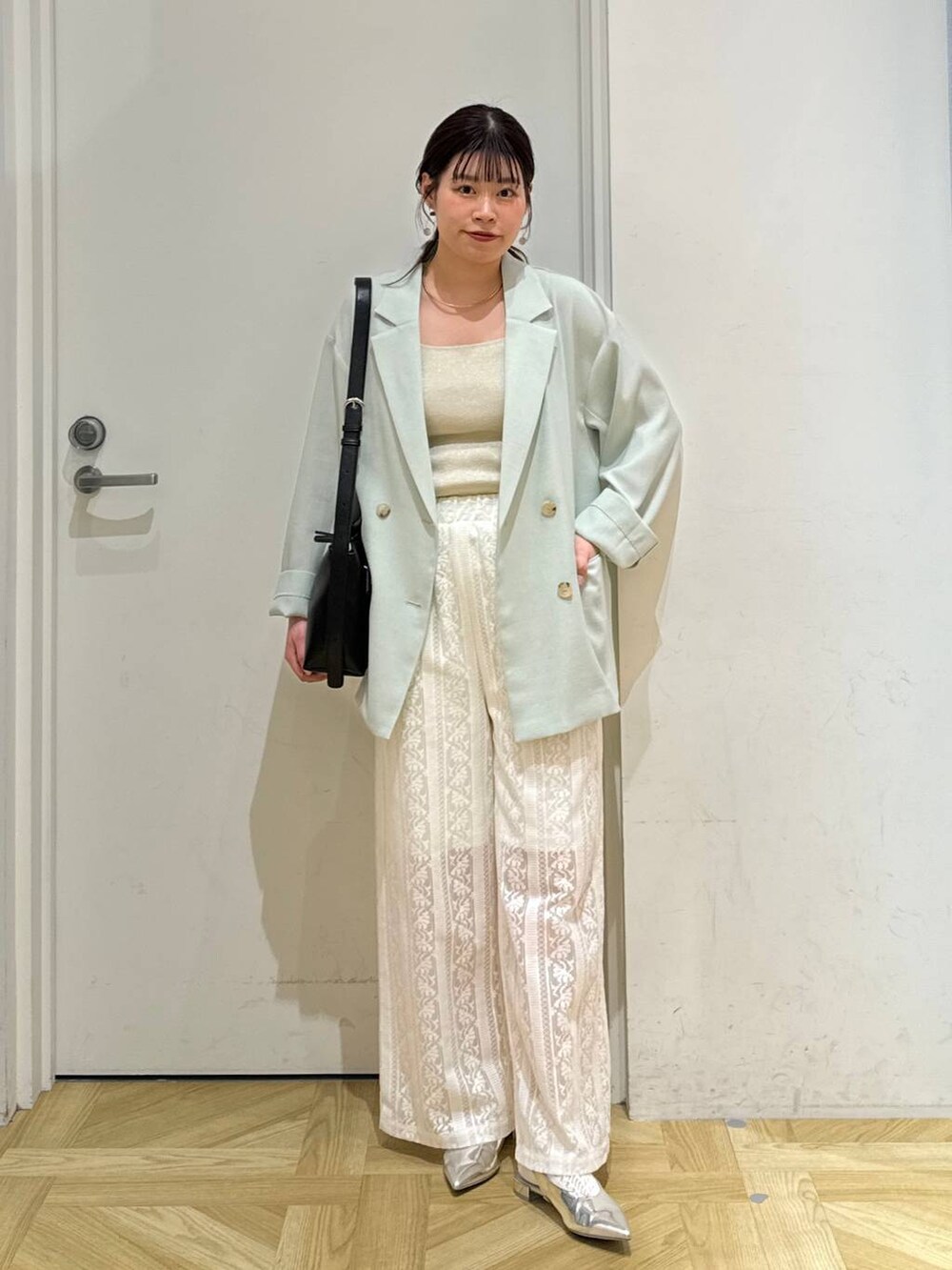 グリーン系のテーラードジャケット、ゴールド系のタンクトップ、シルバー系のパンプスを着用したレディースの春コーディネートの2枚目の写真