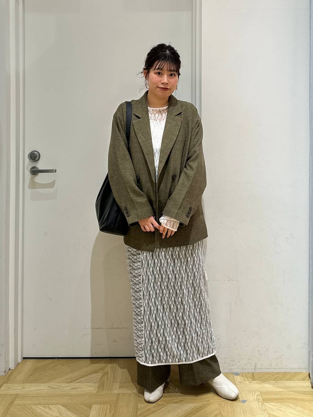 ブラック系のショルダーバッグ、ホワイト系のブーツ、ブラウン系のスラックスを着用したレディースの春コーディネートの3枚目の写真