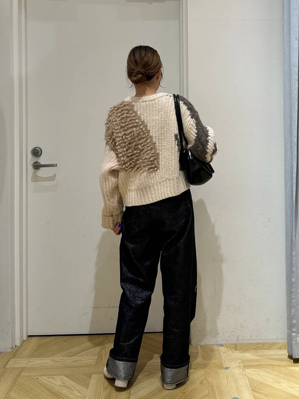 グレー系のデニムパンツ、ブラック系のショルダーバッグ、ホワイト系のブーツを着用したレディースの冬コーディネートの4枚目の写真