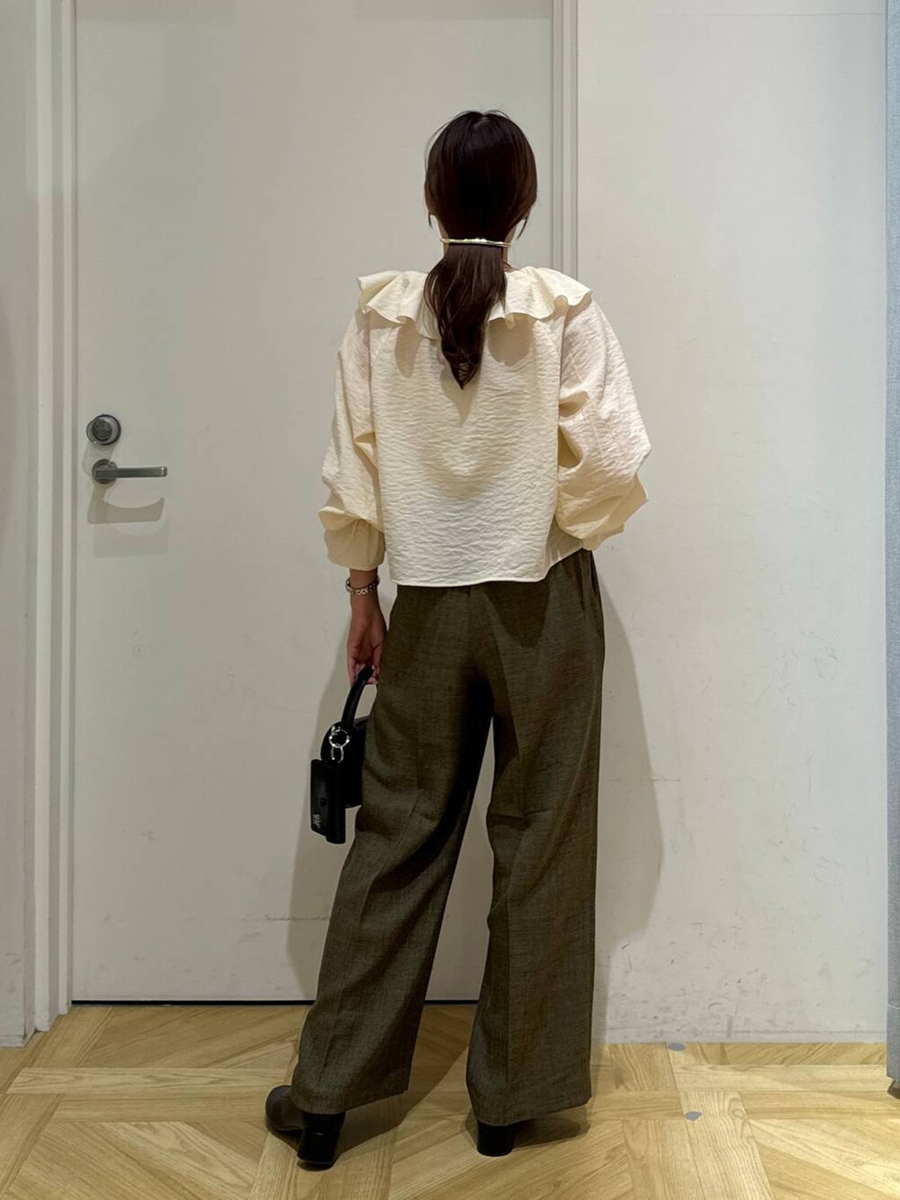 ブラック系のブーツ、ブラウン系のスラックス、ホワイト系のキャミソールを着用したレディースの春コーディネートの6枚目の写真