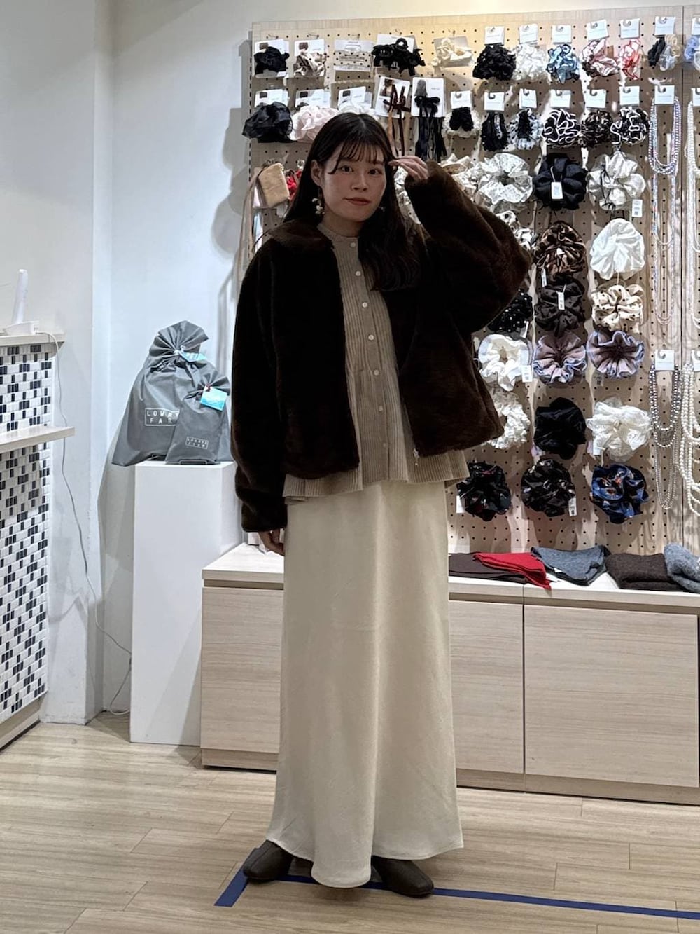 ホワイト系のスカート、ブラウン系のブルゾン、ベージュ系のカーディガン/ボレロを着用したレディースの冬コーディネートの4枚目の写真