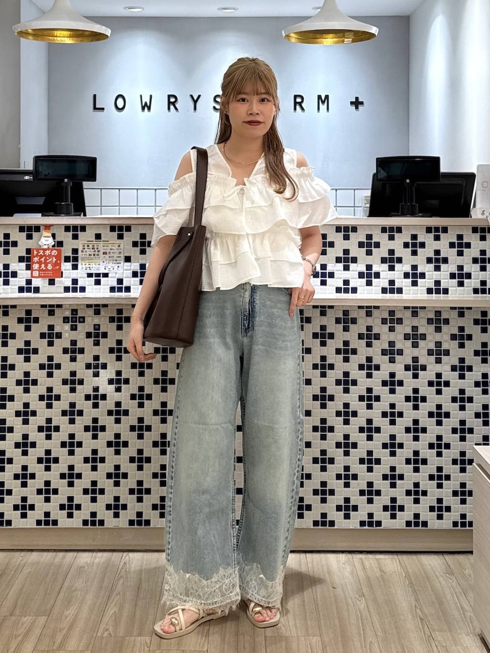 ブルー系のデニムパンツ、ホワイト系のサンダル、ブラウン系のトートバッグを着用したレディースの夏コーディネートの4枚目の写真