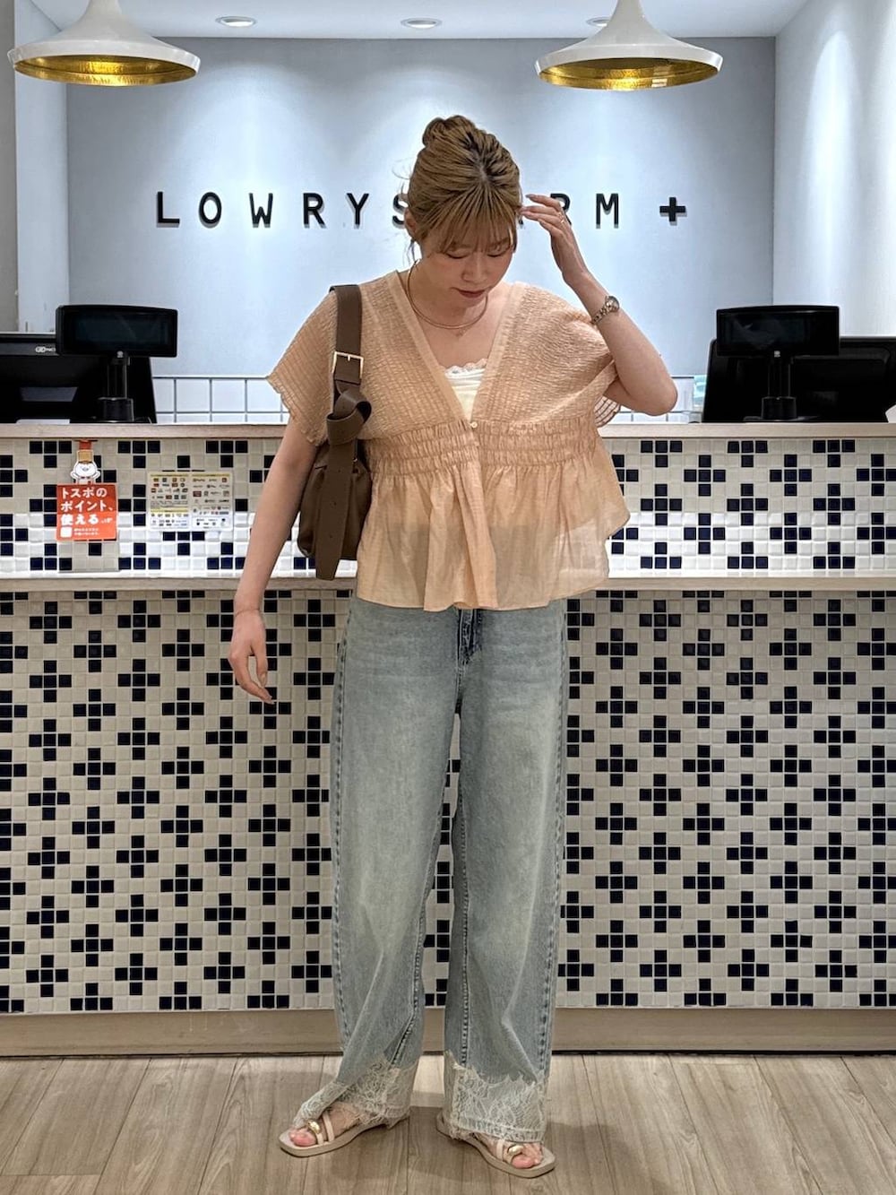 ブルー系のデニムパンツ、ホワイト系のサンダル、ホワイト系のショルダーバッグを着用したレディースの夏コーディネートの2枚目の写真