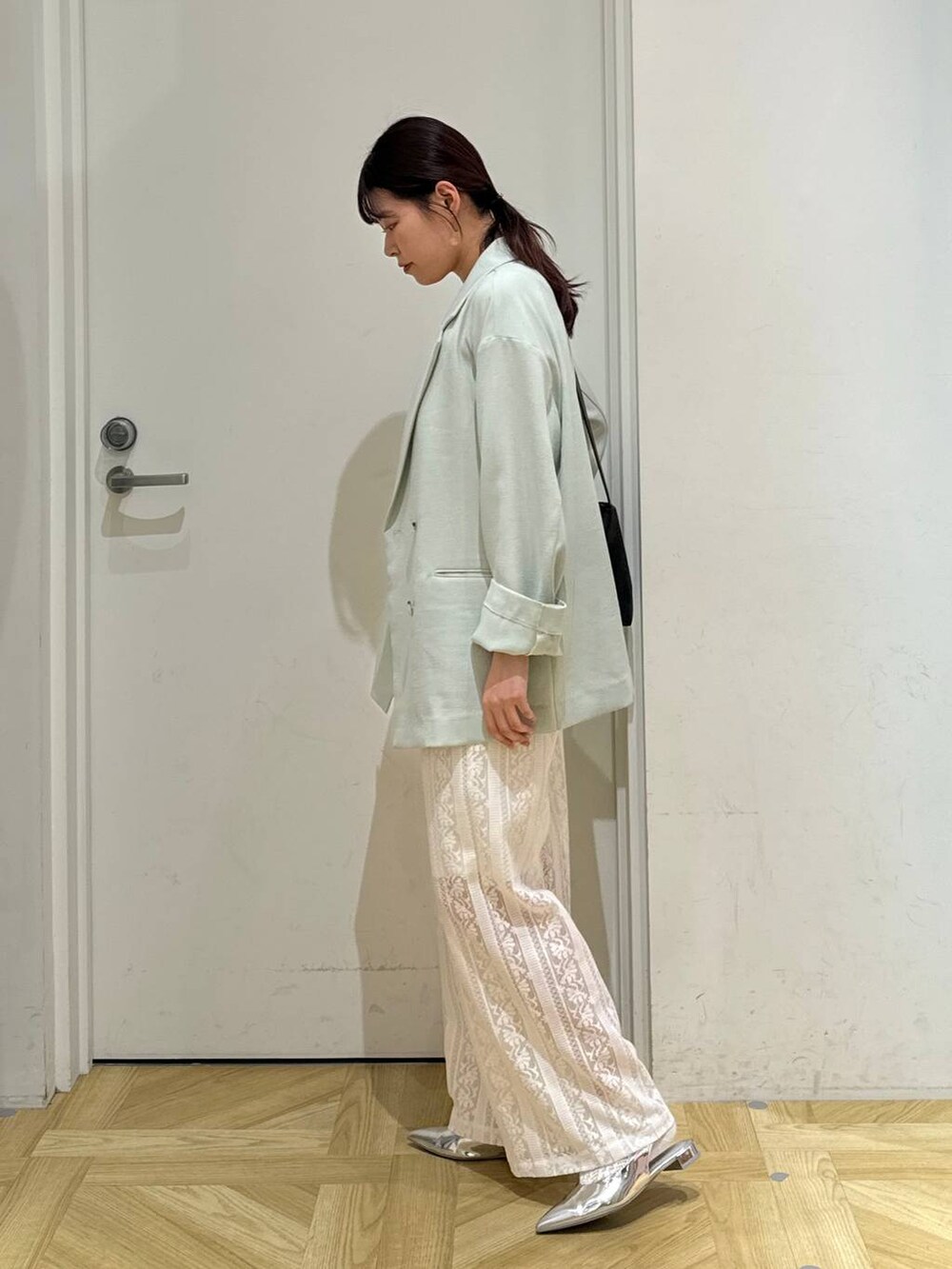 グリーン系のテーラードジャケット、ゴールド系のタンクトップ、シルバー系のパンプスを着用したレディースの春コーディネートの3枚目の写真