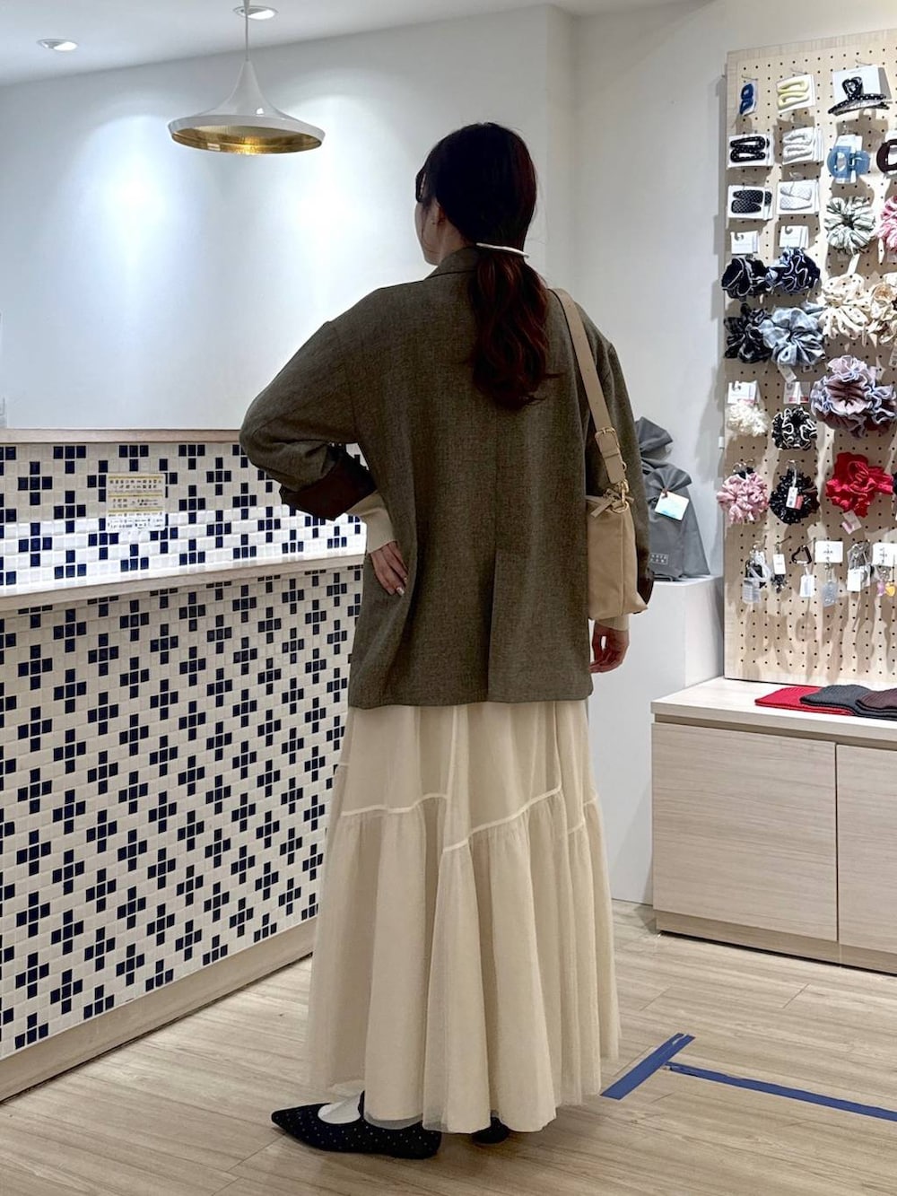 ブラック系のパンプス、ブラウン系のテーラードジャケット、ベージュ系のショルダーバッグを着用したレディースの春コーディネートの5枚目の写真