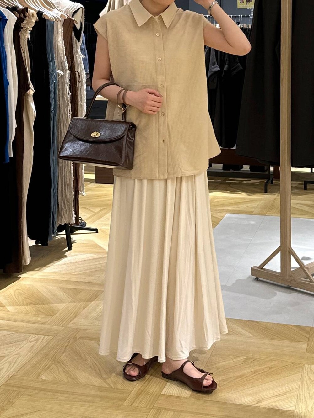 ブラウン系のサンダル、ホワイト系のスカート、ブラウン系のボストンバッグを着用したレディースの夏コーディネートの3枚目の写真