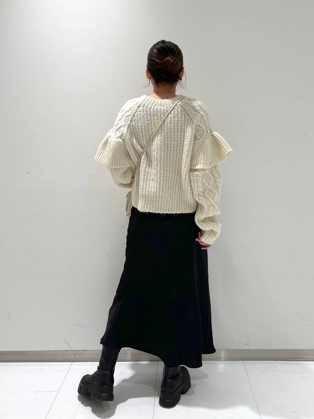 ホワイト系のショルダーバッグ、ブラック系のブーツ、ホワイト系のニット/セーターを着用したレディースの冬コーディネートの3枚目の写真