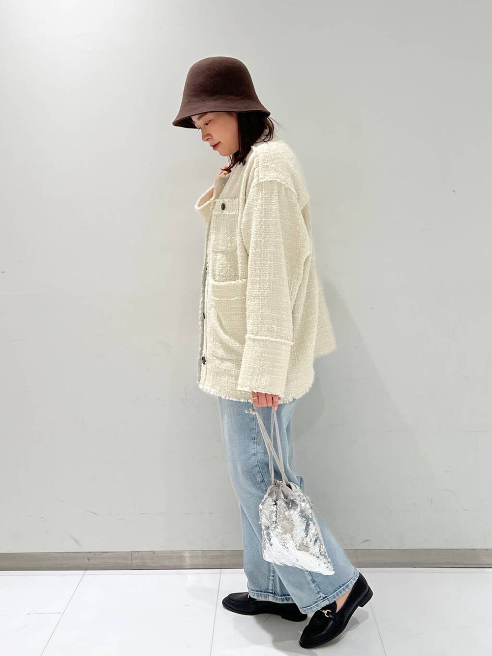 ブルー系のデニムパンツ、ブラック系のローファー、ホワイト系のノーカラージャケットを着用したレディースの秋コーディネートの4枚目の写真