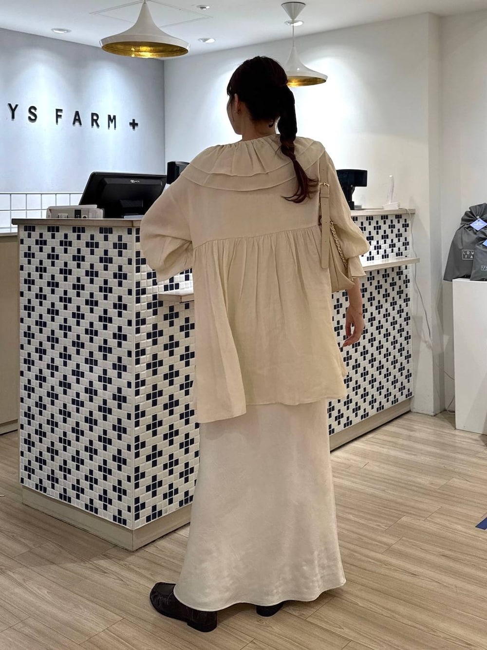 ホワイト系のスカート、ベージュ系のショルダーバッグ、ブラウン系のローファーを着用したレディースの春コーディネートの5枚目の写真