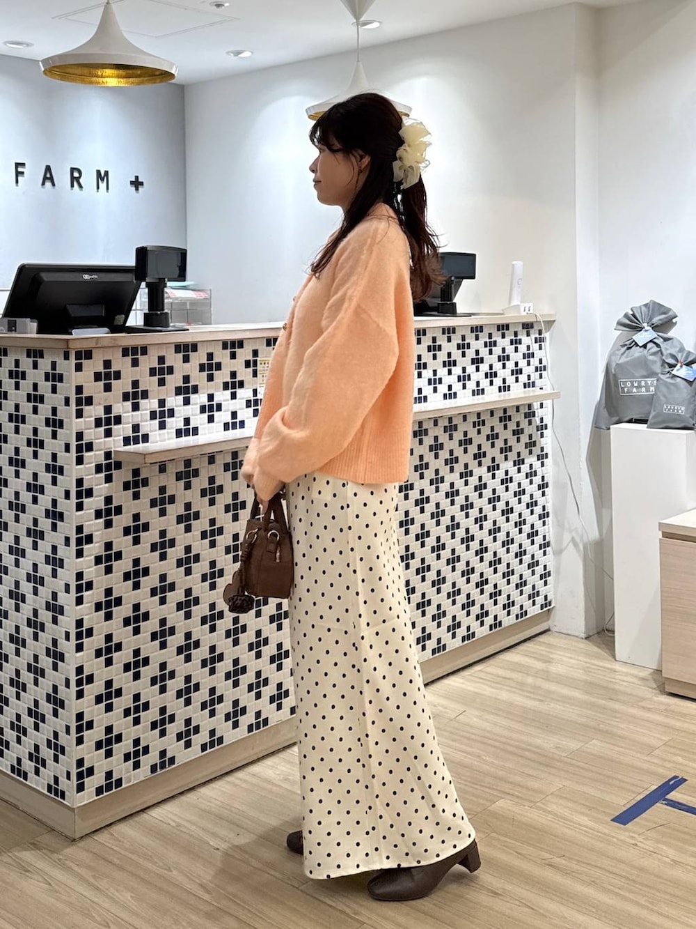 ホワイト系のスカート、ブラウン系のボストンバッグ、ブラウン系のブーツを着用したレディースの冬コーディネートの4枚目の写真