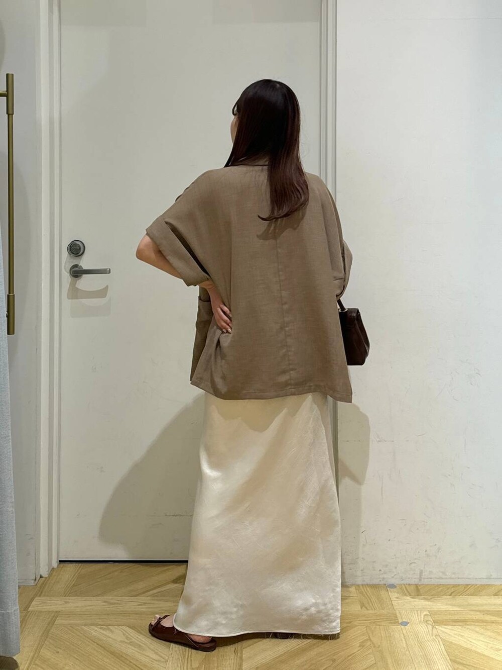 ブラウン系のスカート、ベージュ系のテーラードジャケット、ブラウン系のサンダルを着用したレディースの夏コーディネートの4枚目の写真